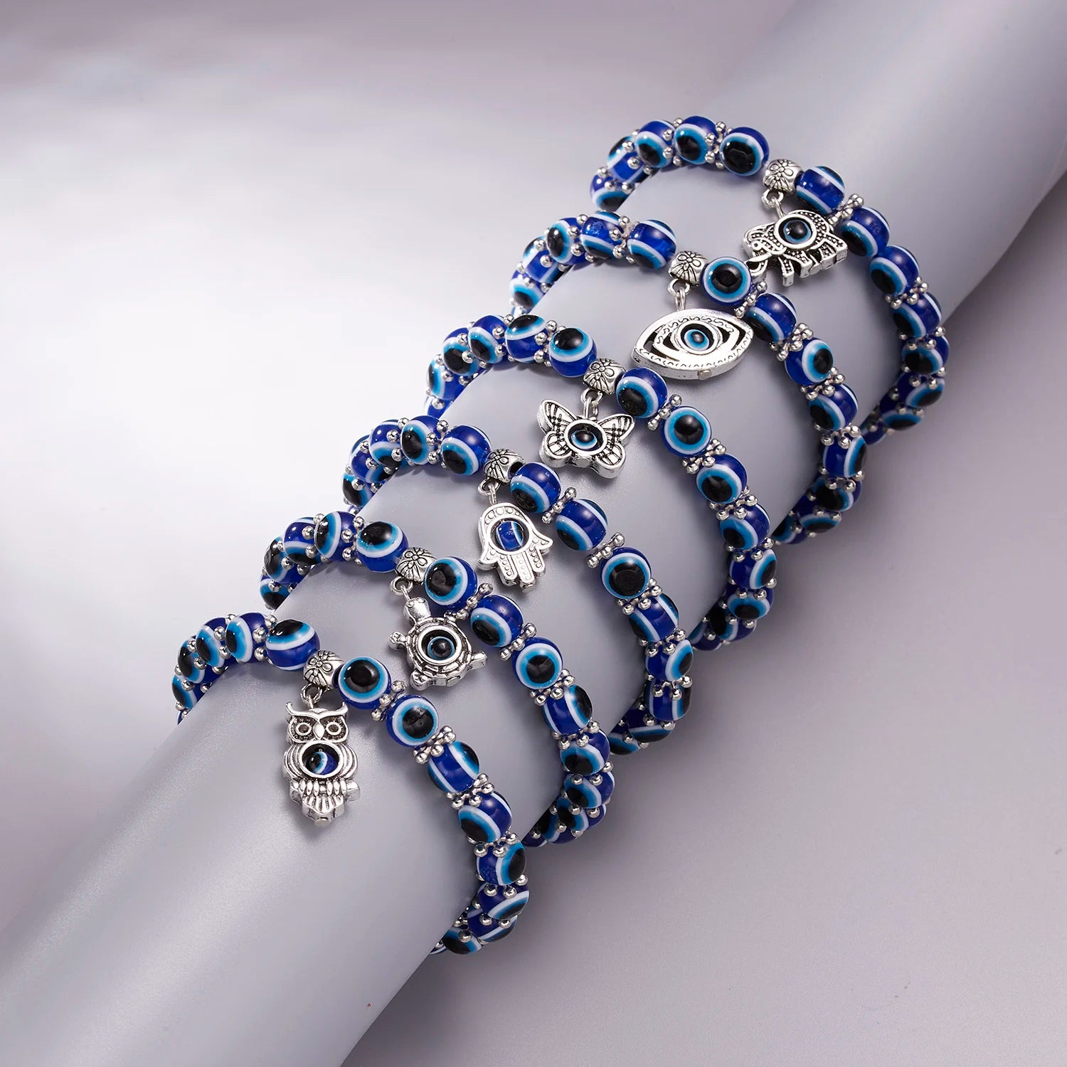 Blue and silver bracelet with eye and owl charms on a light gray background