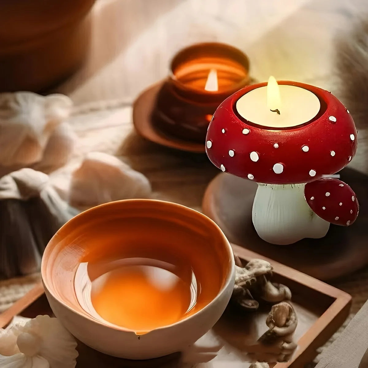 Tea cup with a mushroom-shaped candle holder on a soft fabric background
