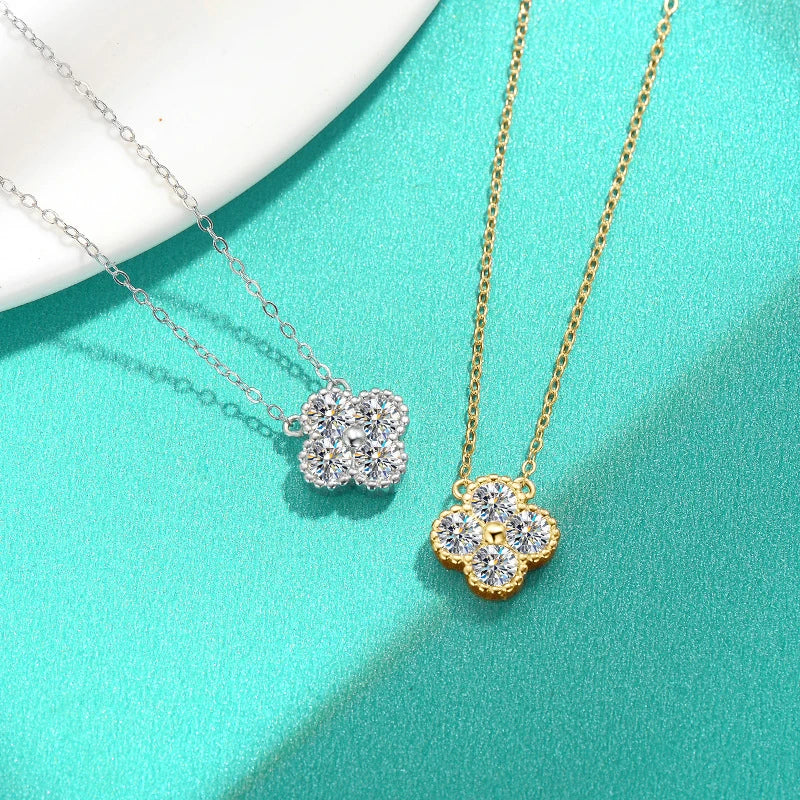 Two floral-shaped pendants on gold and silver chains against a teal background