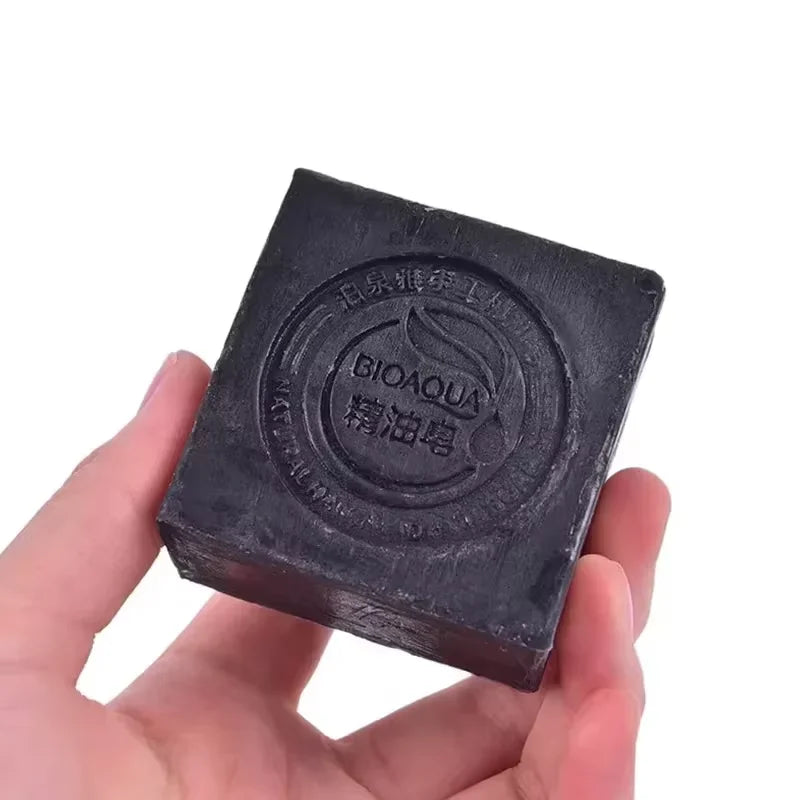 Black soap bar held in a hand with 'BIOAQUA' branding on a white background