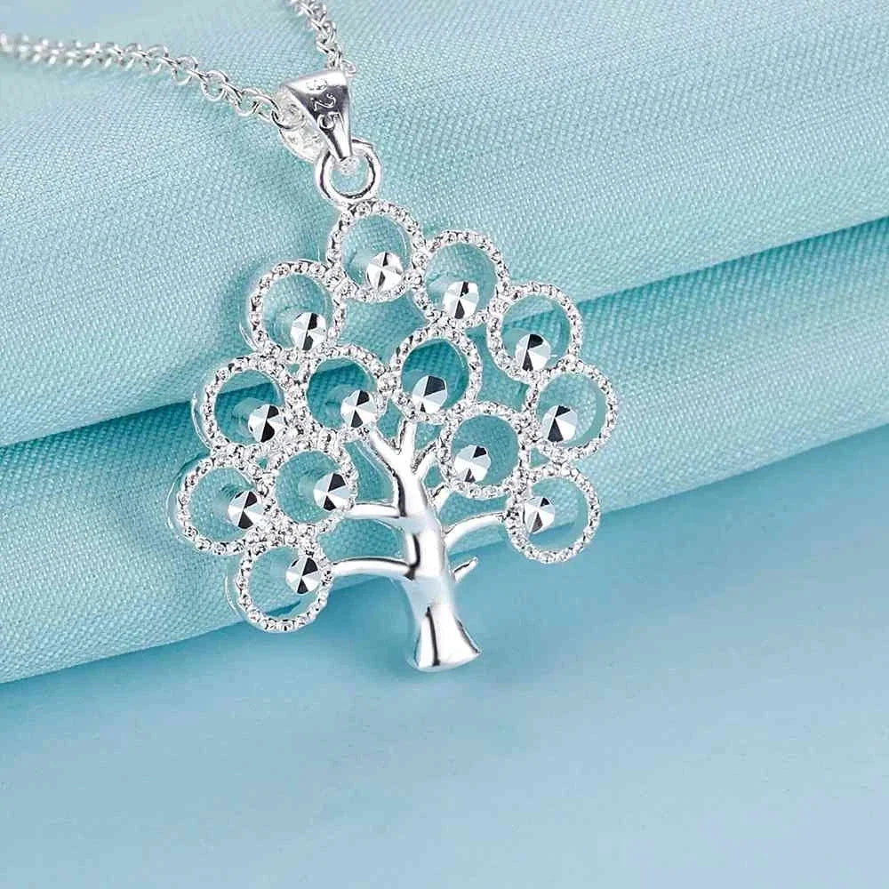 Silver tree-shaped pendant necklace on a light blue satin background