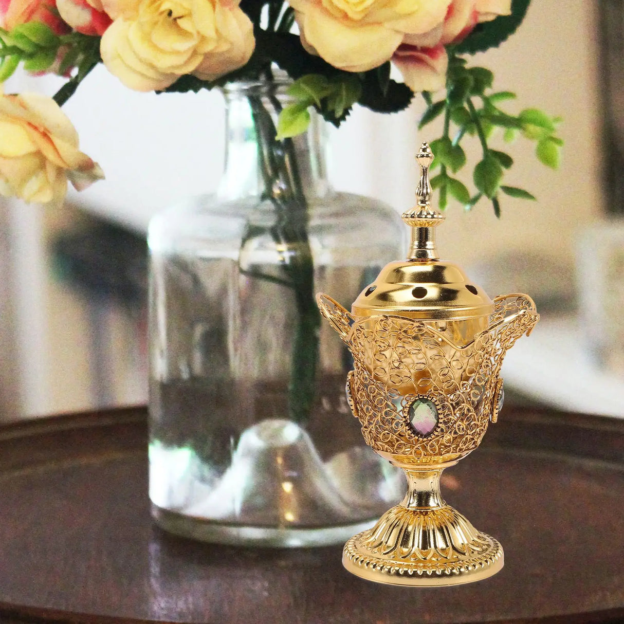 Decorative gold lantern with intricate designs on a table with flowers in the background