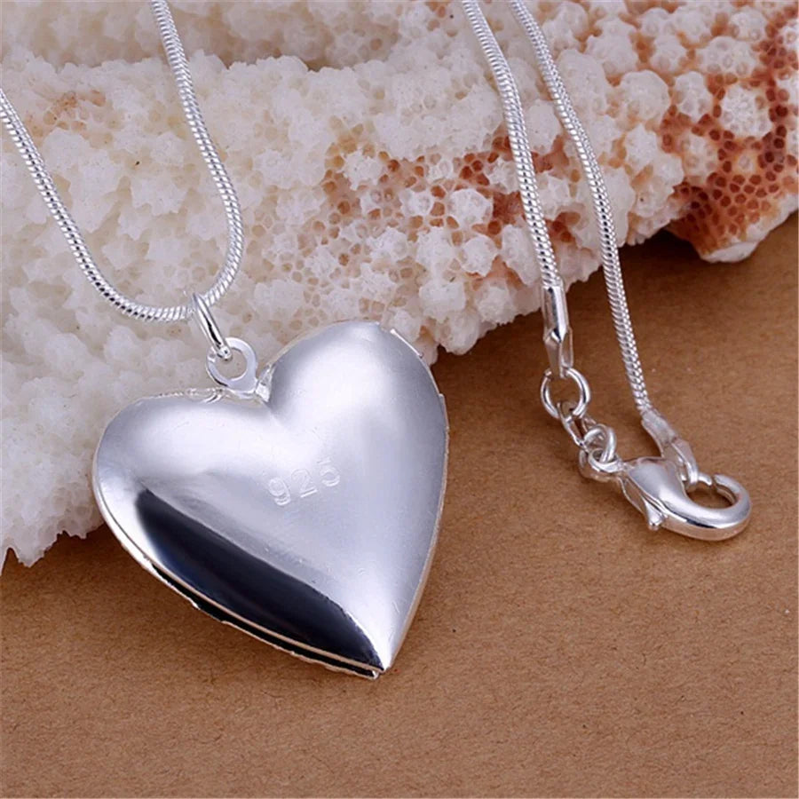 Silver heart-shaped locket necklace on a textured surface