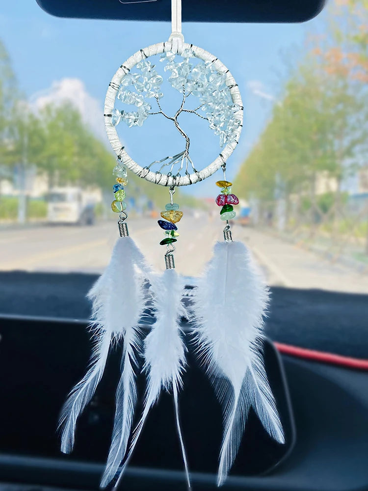 Car dashboard with a white feathered dreamcatcher ornament.