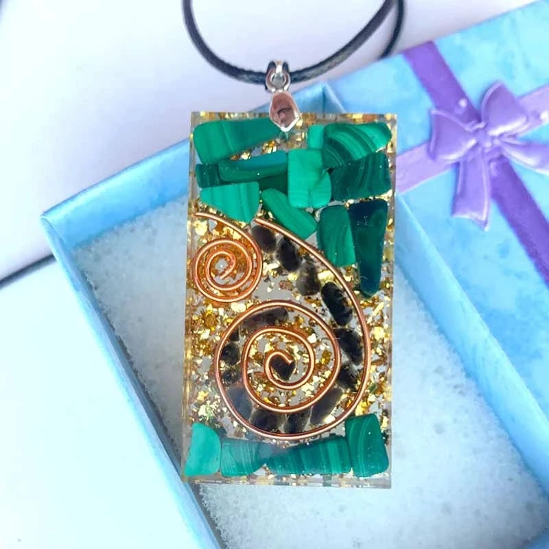 Decorative pendant with green stones and gold patterns on a blue gift box background