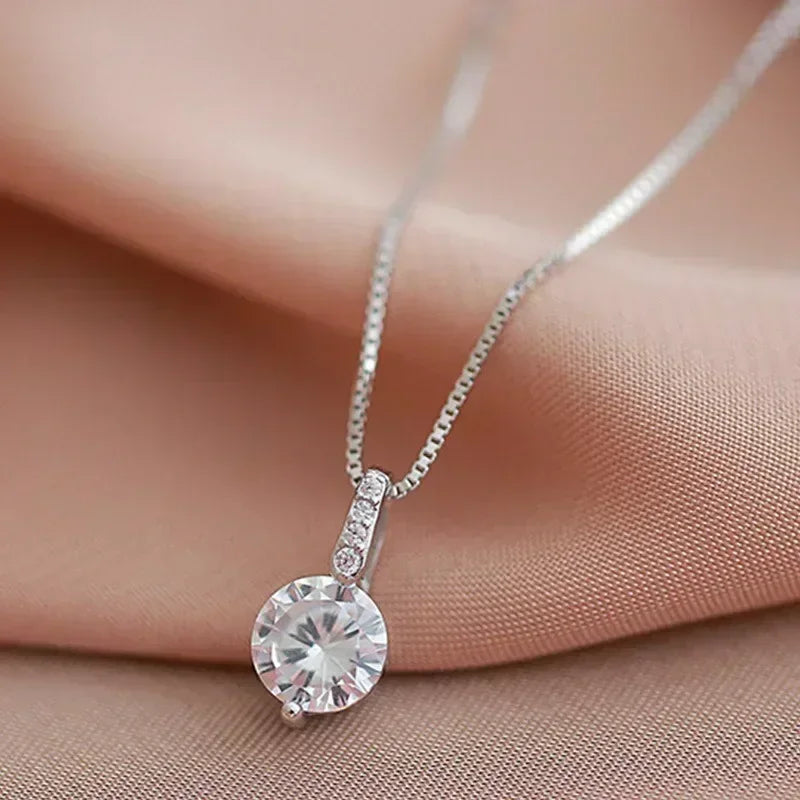 Silver necklace with a round pendant on a soft pink fabric background
