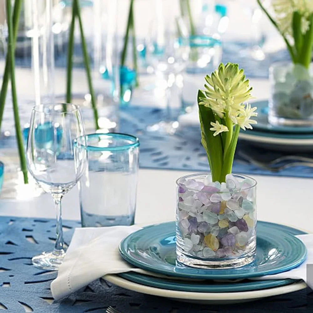 Decorative table setting with a glass vase containing flowers on a blue plate.