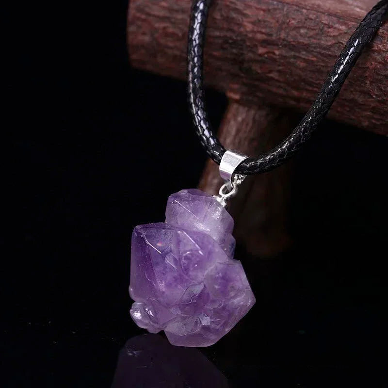 Amethyst crystal pendant on a black cord against a dark background