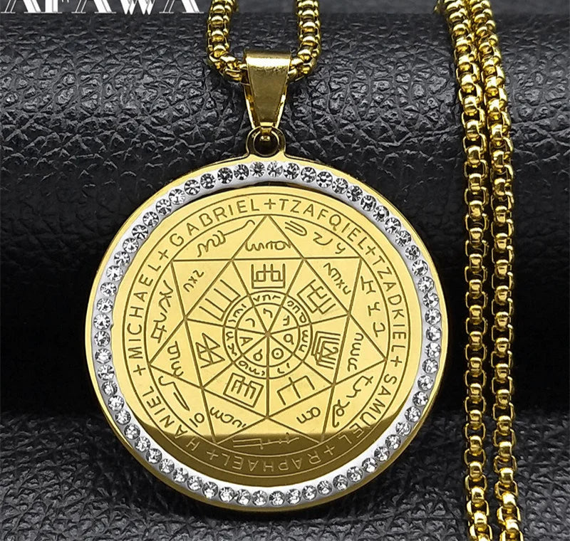 Gold pendant with intricate design and chain on a textured black background