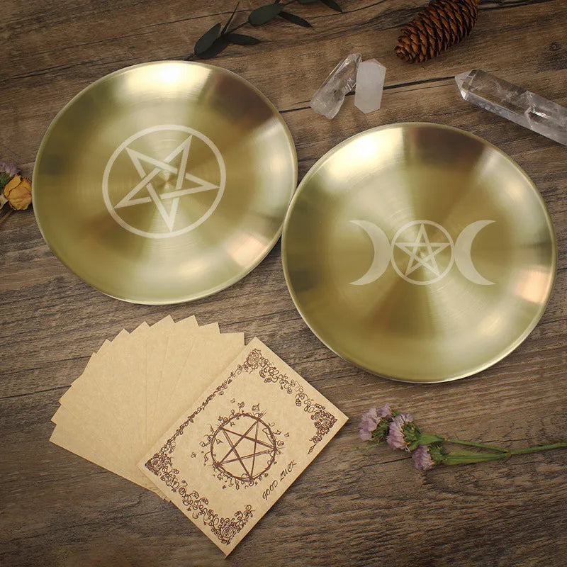 Two gold plates with star and moon symbols on a wooden surface with cards and crystals.