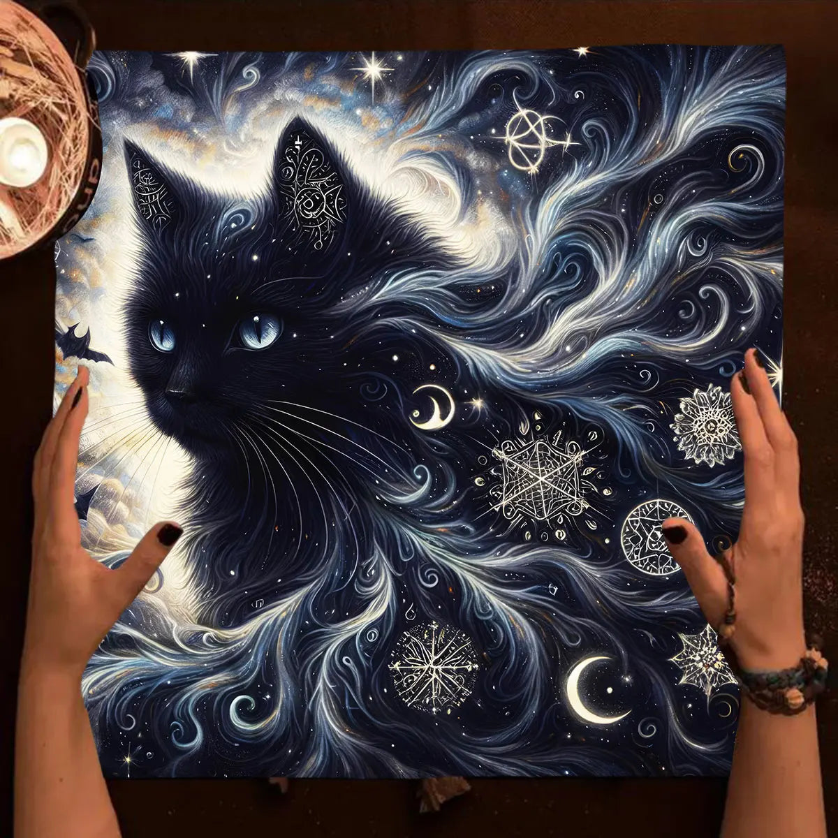 Artistic depiction of a black cat with celestial elements and hands holding the artwork.