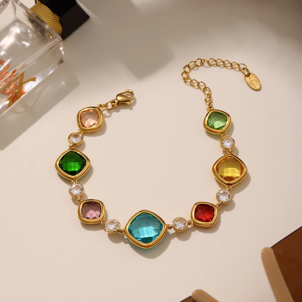 Gold bracelet with colorful gemstones on a light background