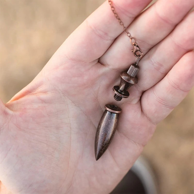 Bronze pendant necklace held in a hand with a blurred background