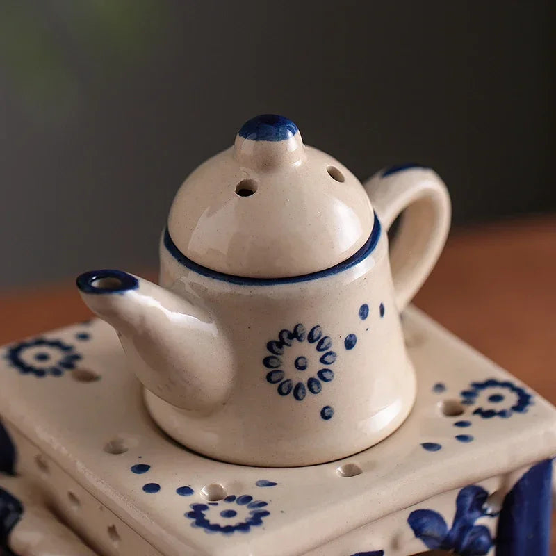 Ceramic teapot with blue floral patterns on a matching stand against a dark background
