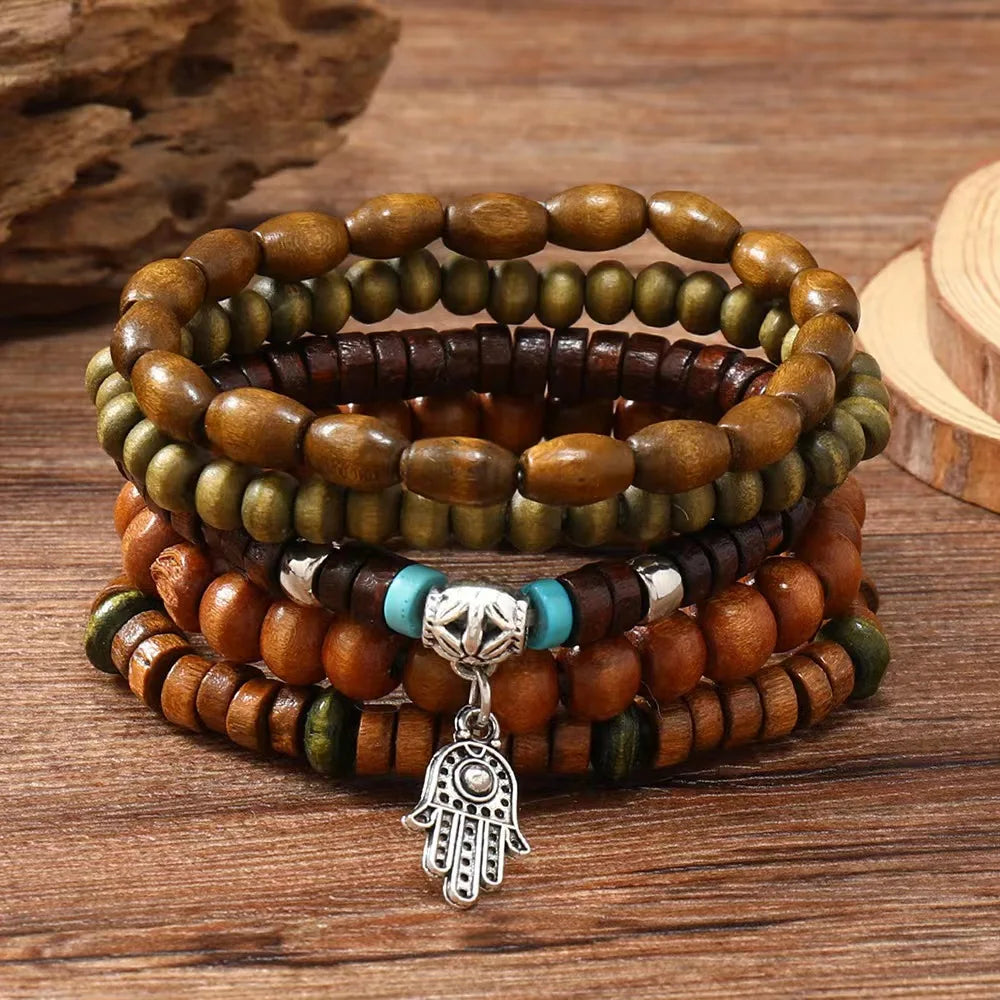 Stack of wooden beaded bracelets with a Hamsa hand charm on a wooden surface
