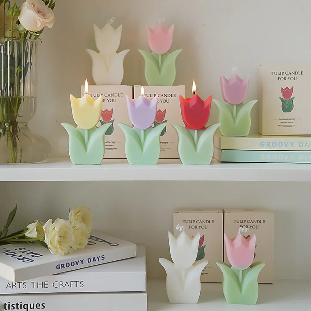 Colorful tulip-shaped candles on a shelf with books and flowers.