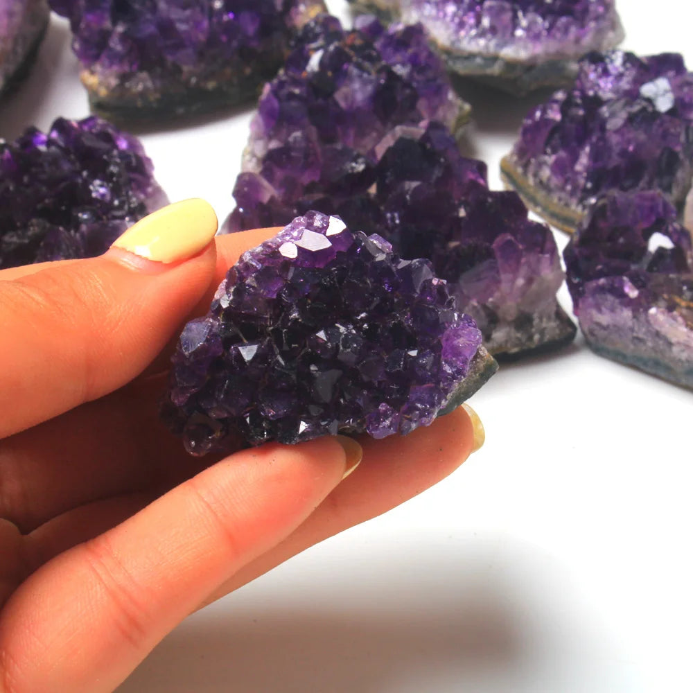Hand holding a purple crystal with more crystals in the background