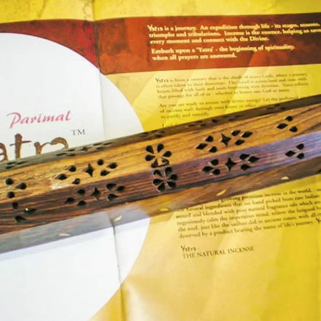 Wooden incense stick with decorative patterns on a yellow background with text