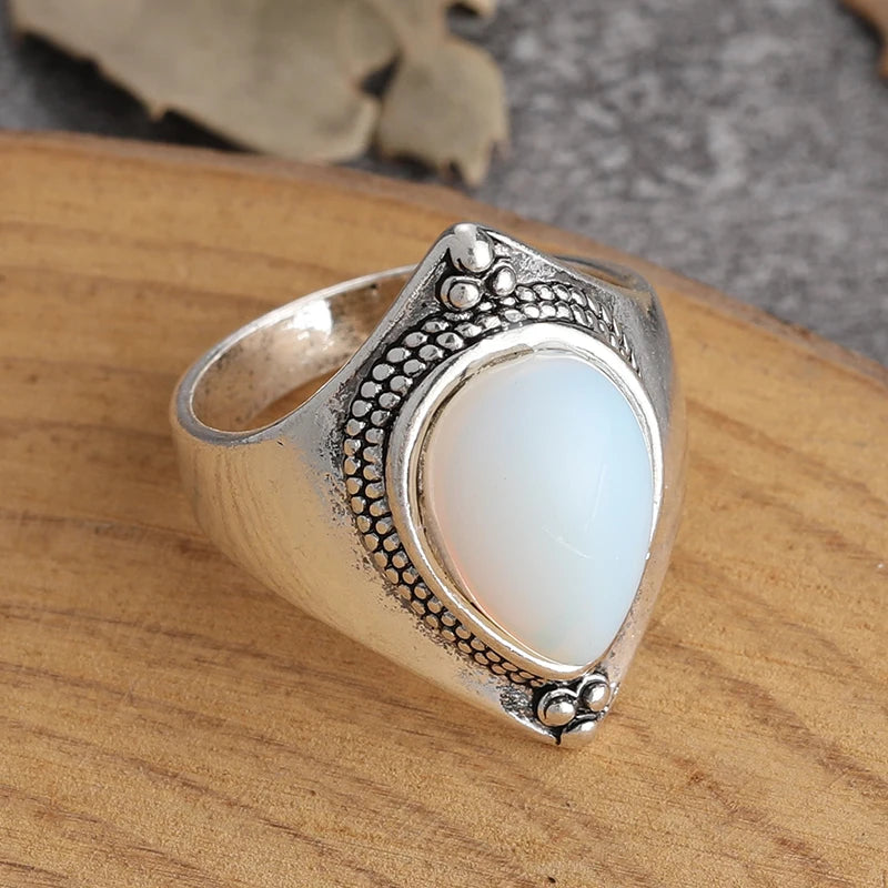 Silver ring with a white stone on a wooden surface