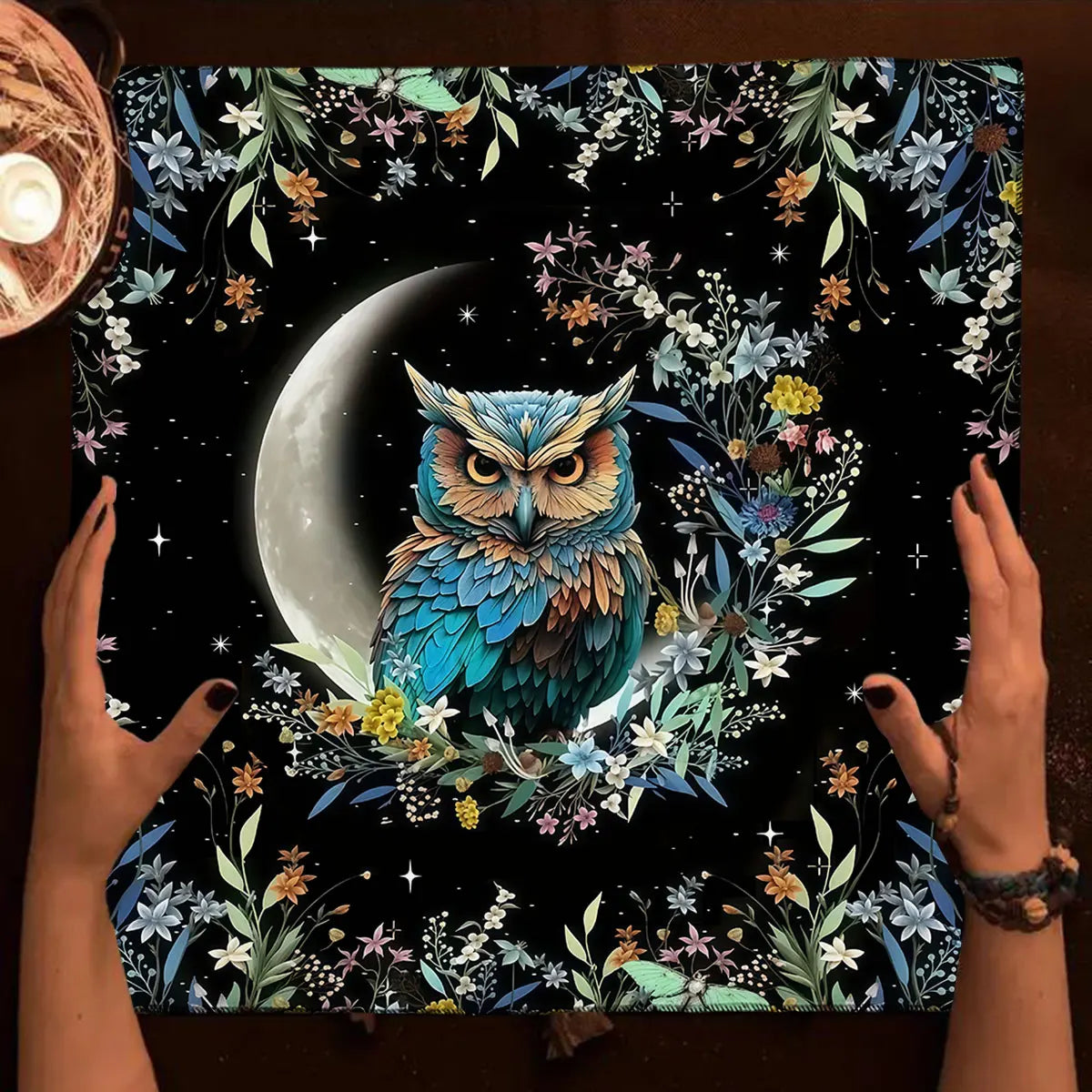 Floral and owl design on a dark background with hands holding it