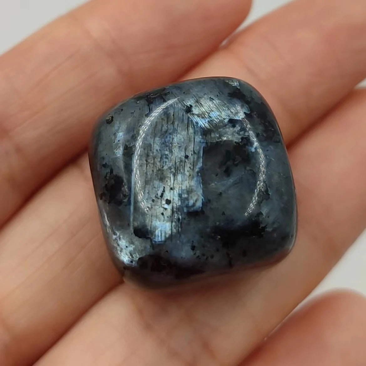 Black stone held in a hand against a neutral background