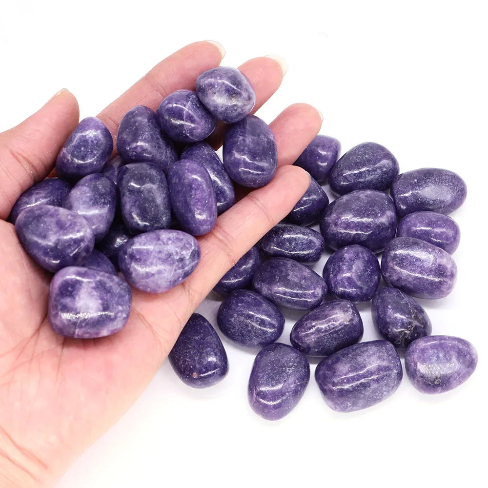 Hand holding purple stones against a white background