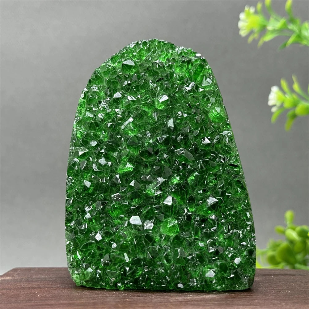 Green crystal rock-like sculpture on a wooden surface with a gray background