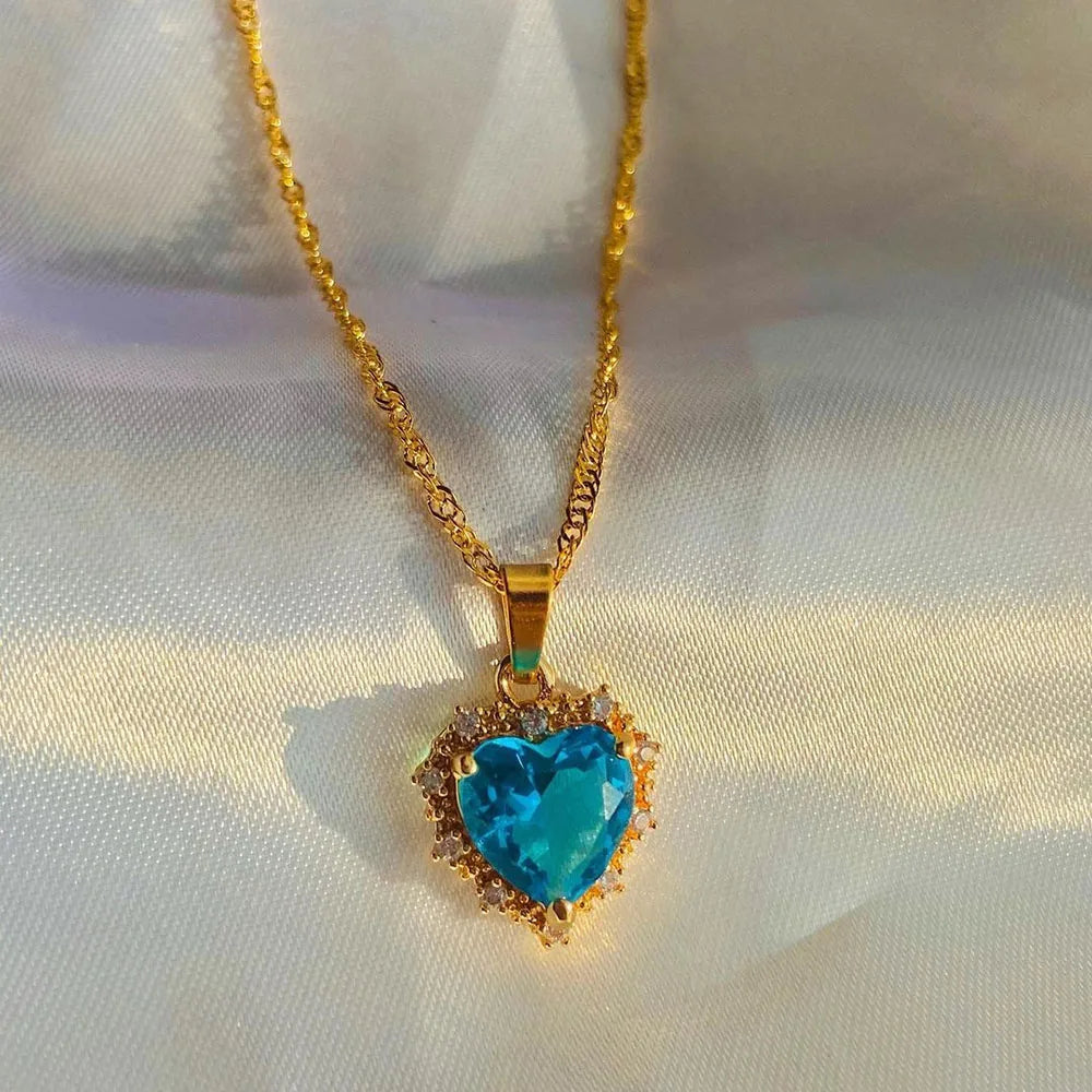 Gold necklace with a turquoise heart-shaped pendant on a white fabric background