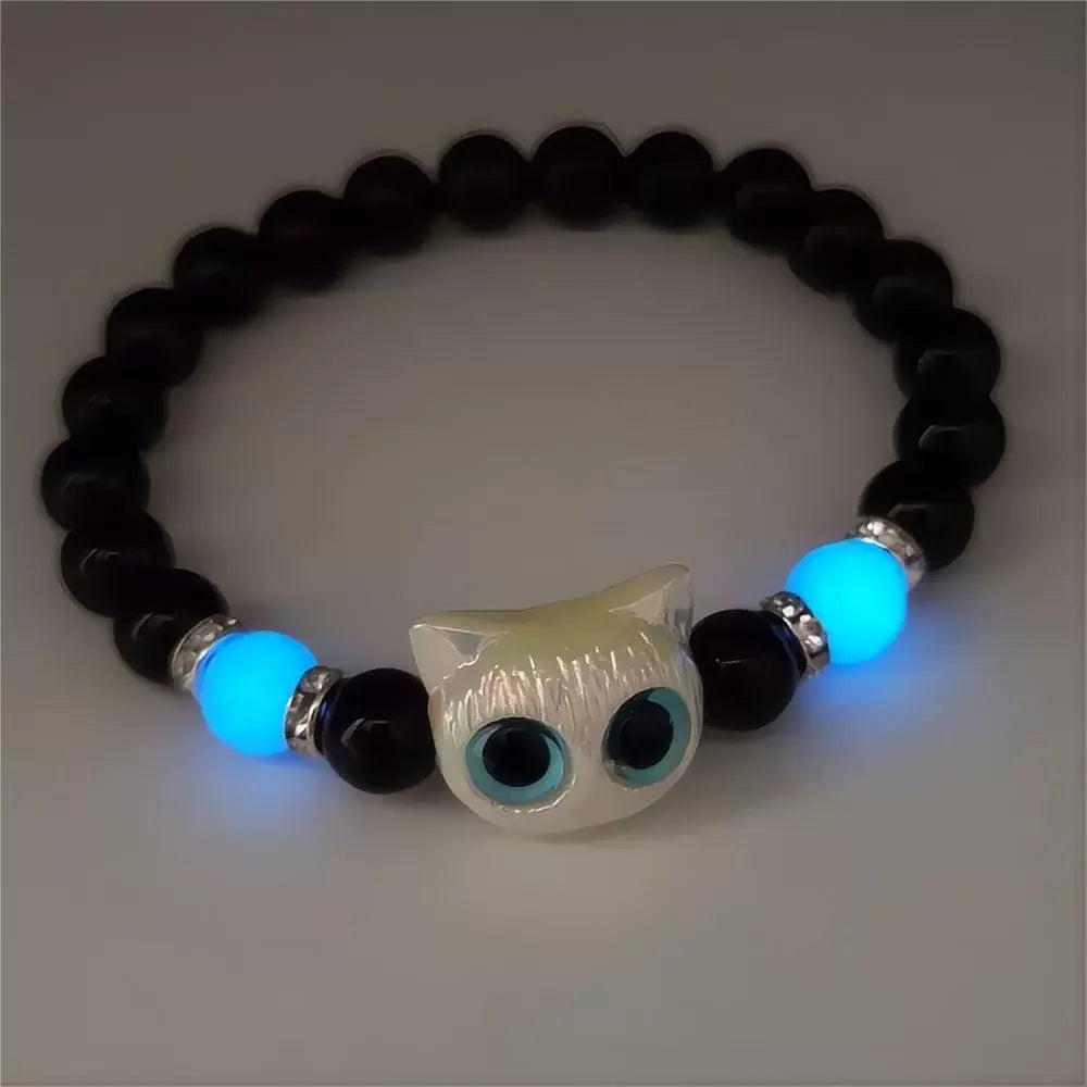Bracelet with black beads, blue accents, and a cat-shaped charm on a light gray background