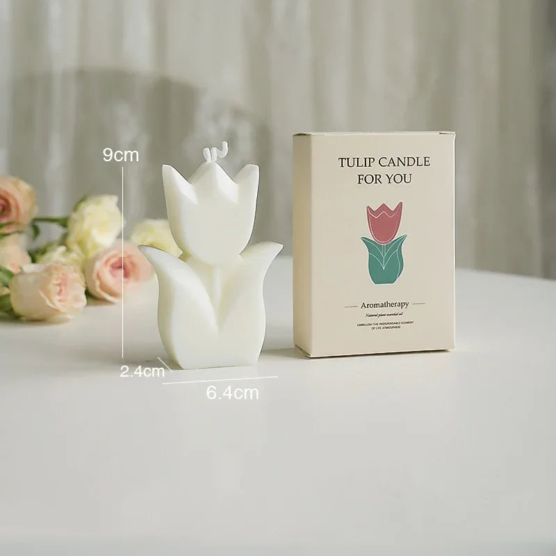 Tulip-shaped candle with packaging and floral arrangement on a light surface