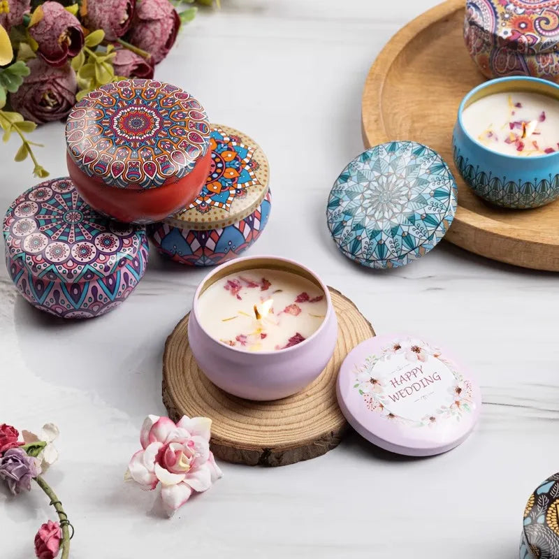 Colorful candles in decorative tins on a white surface with flowers.