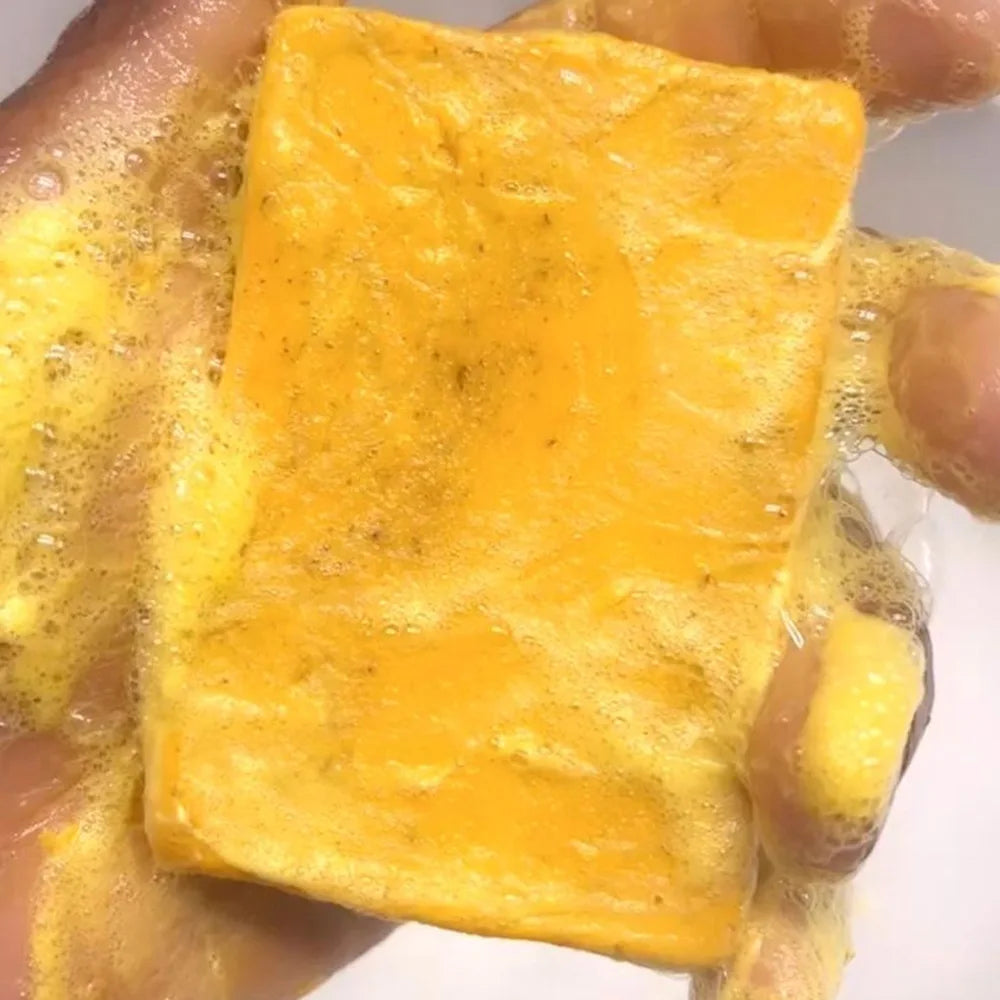 Yellow soap bar with black specks held by a hand