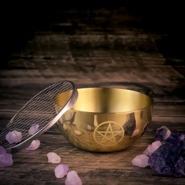 Gold singing bowl with pentacle symbol surrounded by crystals on a wooden surface