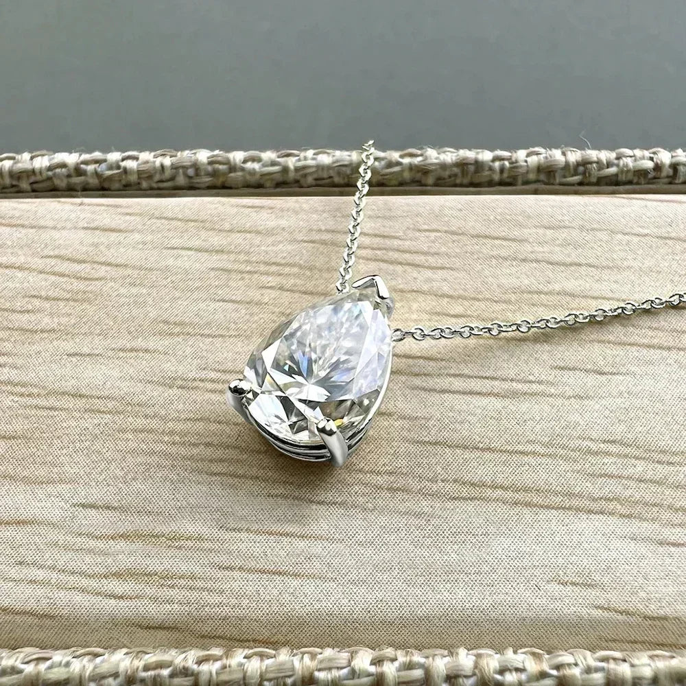 Teardrop-shaped crystal pendant on a chain against a neutral background