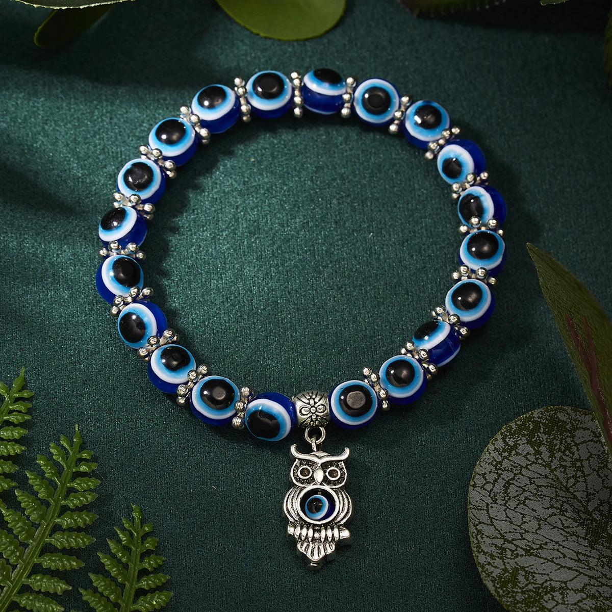 Bracelet with blue and black beads and an owl charm on a green background
