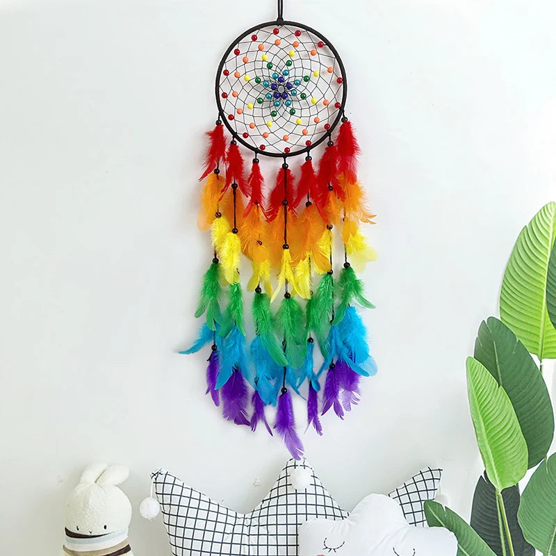 Rainbow-colored dreamcatcher with feathers against a white wall.