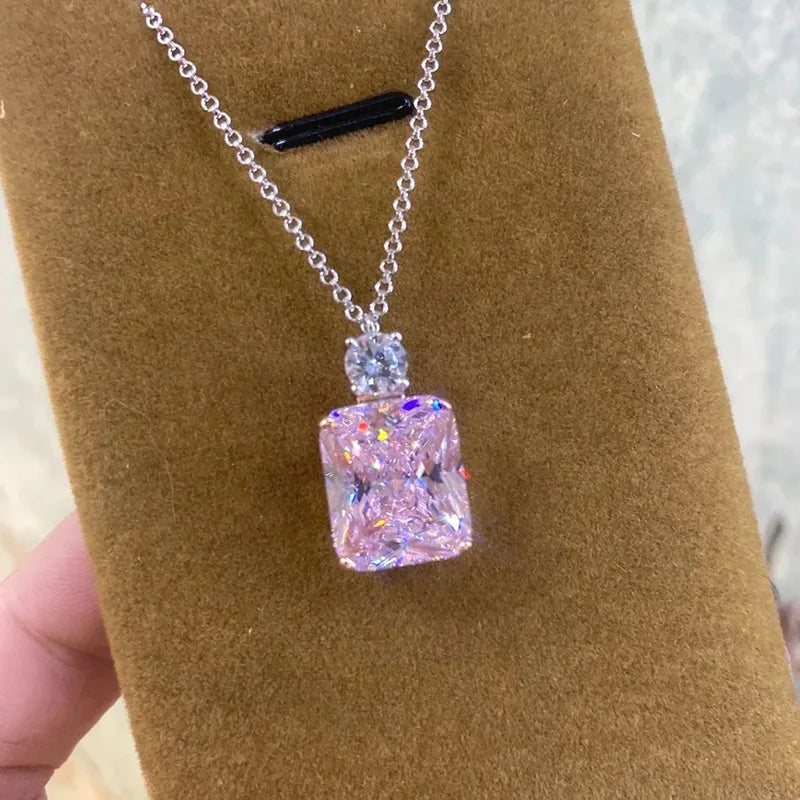 Necklace with a pink diamond pendant on a brown velvet stand.