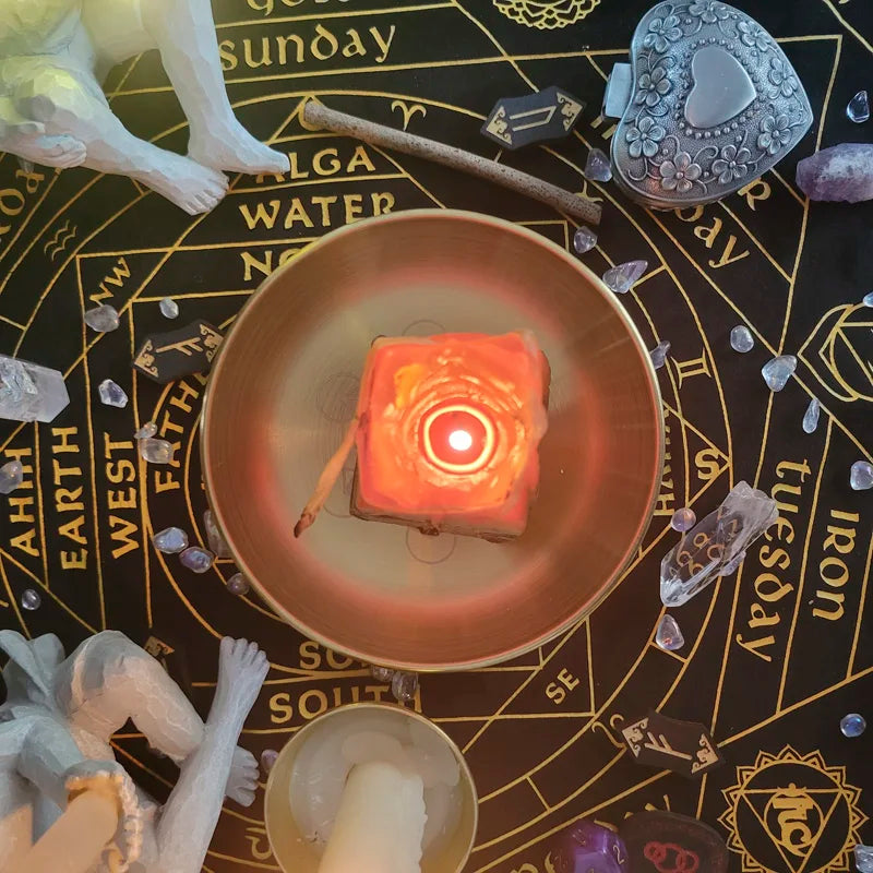 Candle in a bowl on an astrological chart with crystals and figurines.