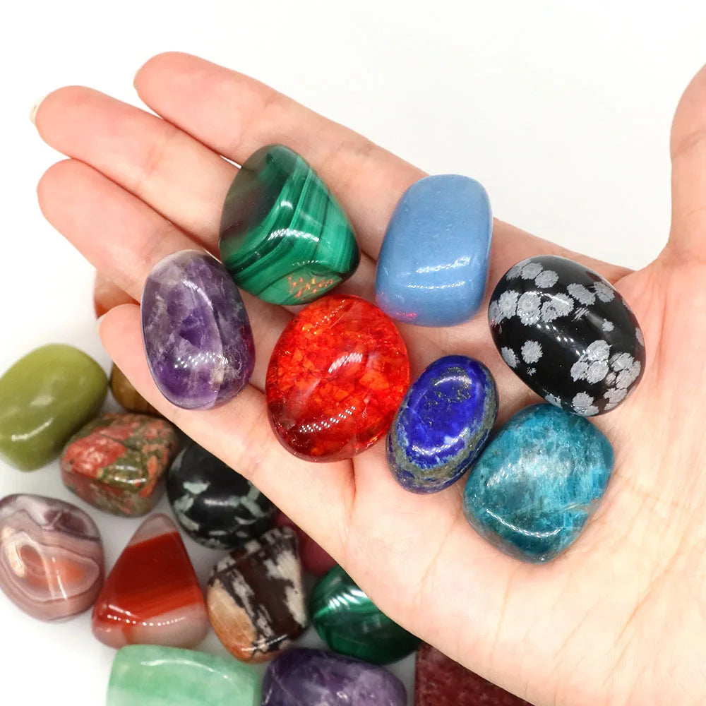 Hand holding a collection of colorful gemstones on a white background