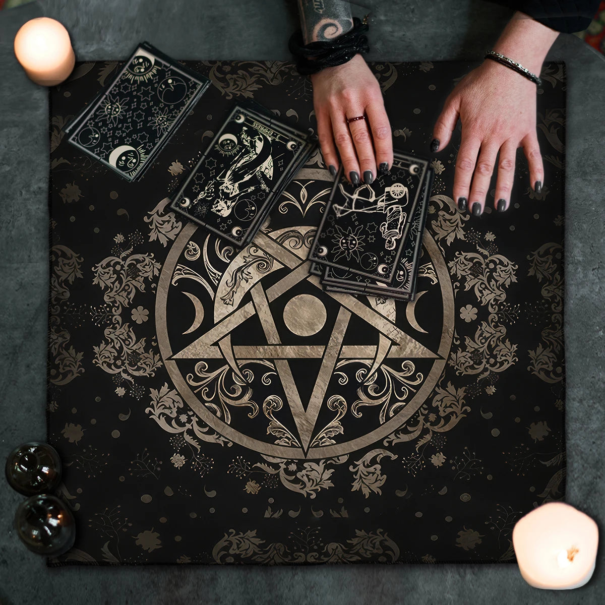 Tarot cards on a black cloth with intricate designs, surrounded by candles and crystals.