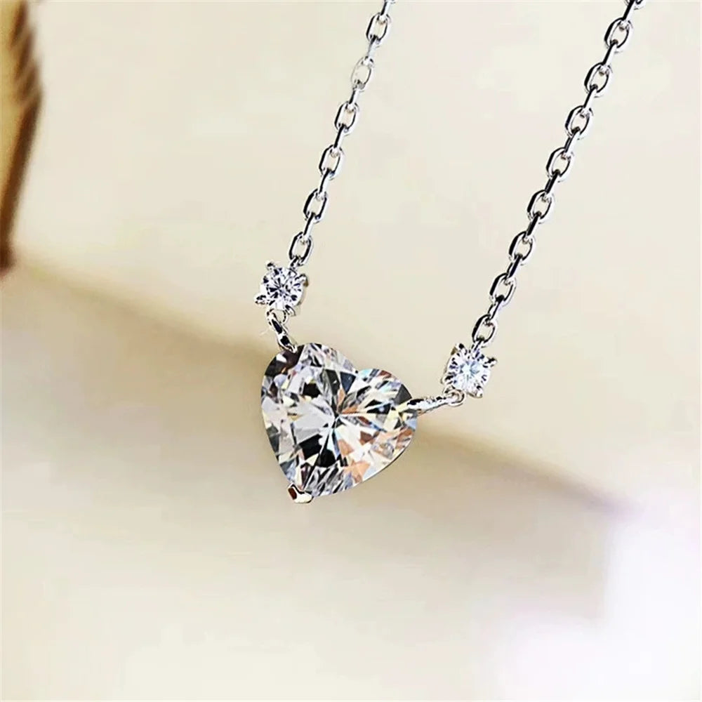 Heart-shaped diamond pendant on a chain against a blurred background