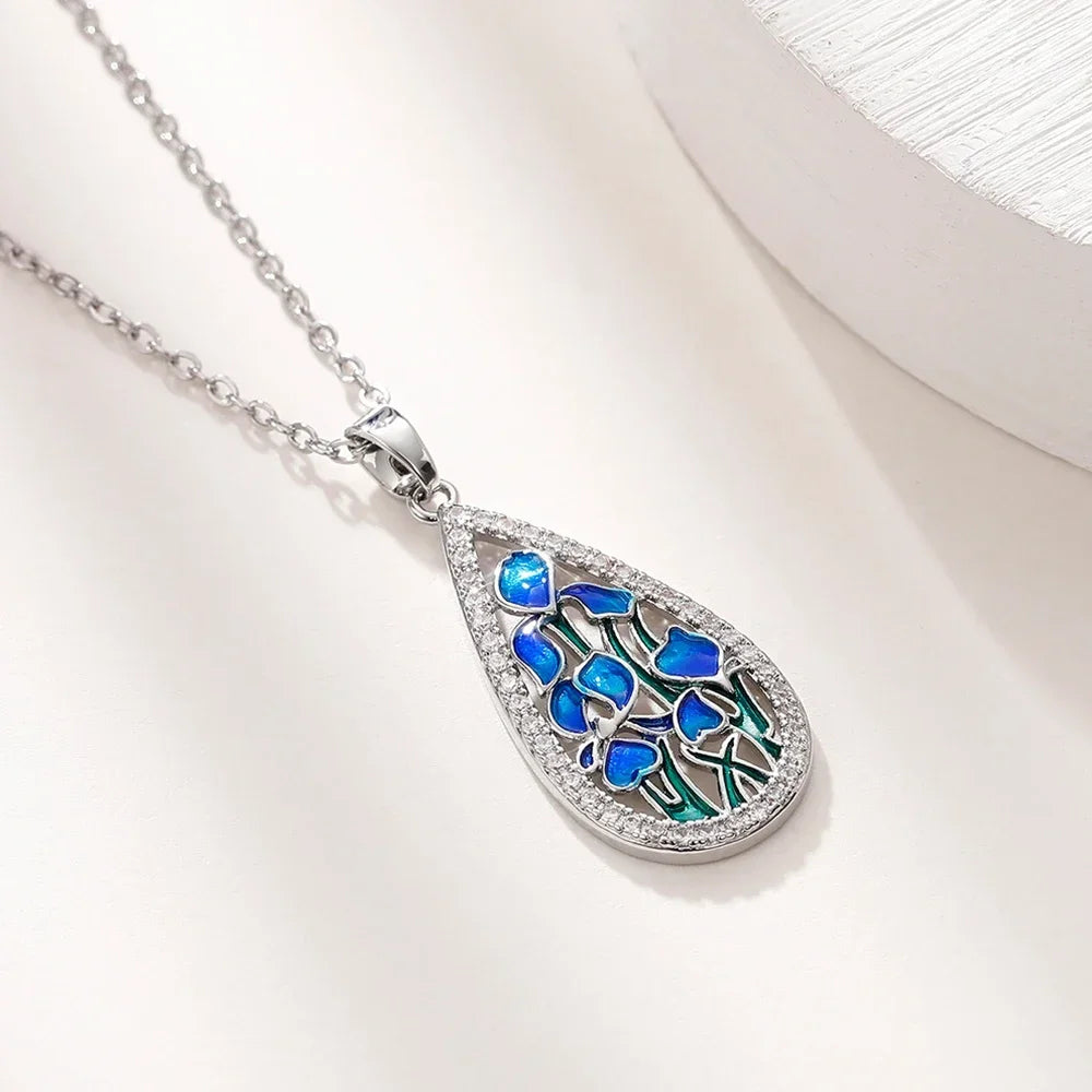 Teardrop-shaped pendant with blue and green design on a white background
