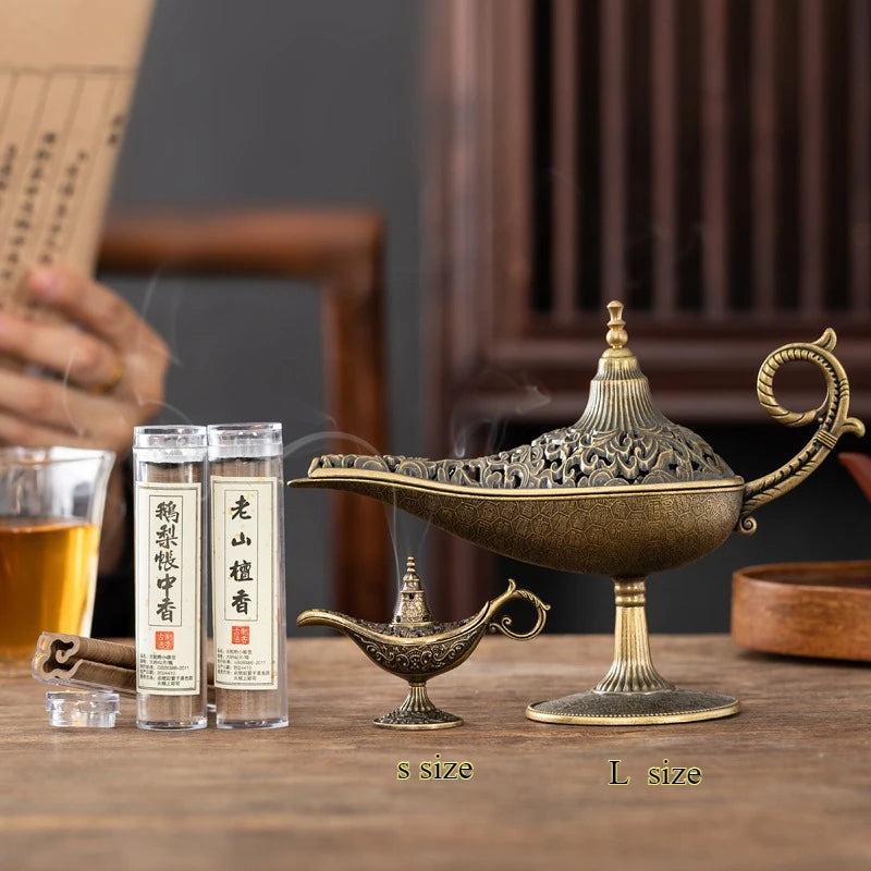 Decorative incense burner with two bottles of incense on a wooden table.