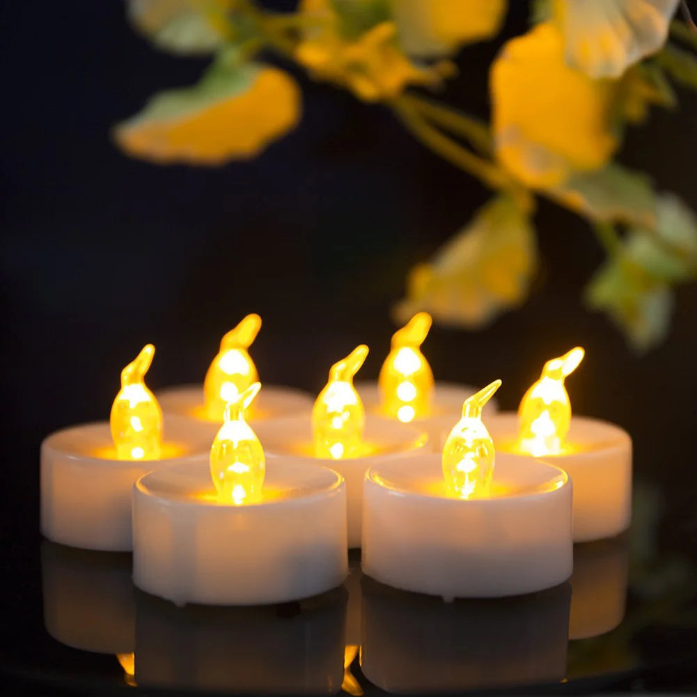 Set of LED candles with flame-like lights on a reflective surface with blurred greenery in the background.