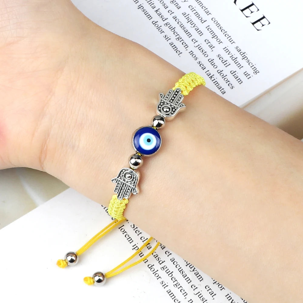 Yellow bracelet with blue evil eye charm on a wrist, placed on a book
