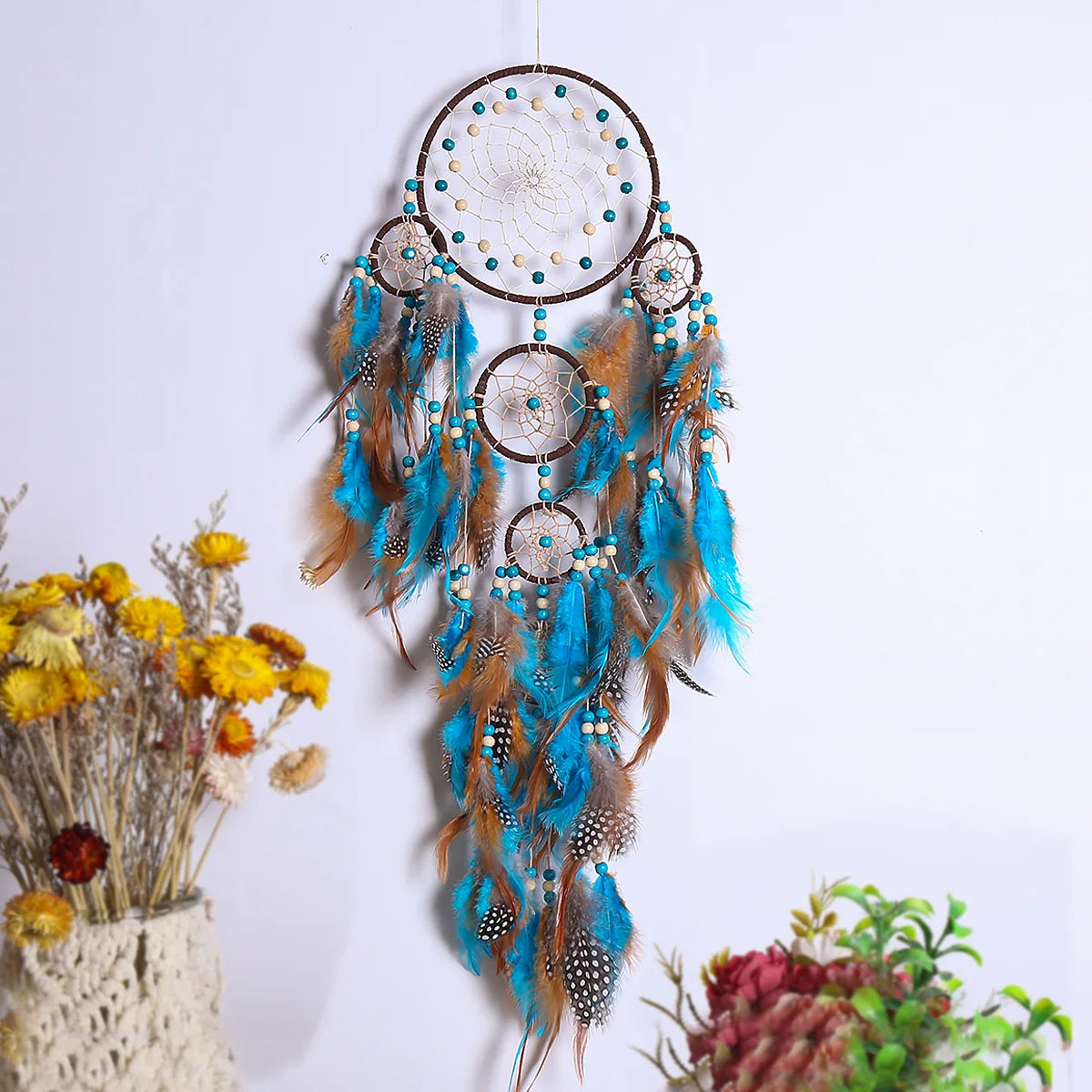Decorative dreamcatcher with feathers and beads on a white background