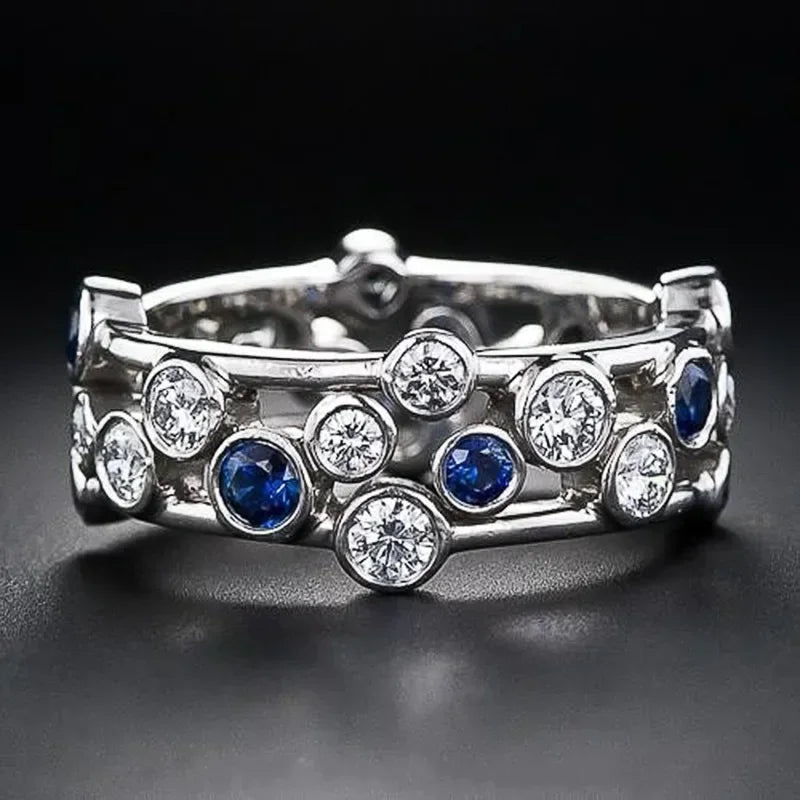 Silver ring with blue and clear gemstones on a black background