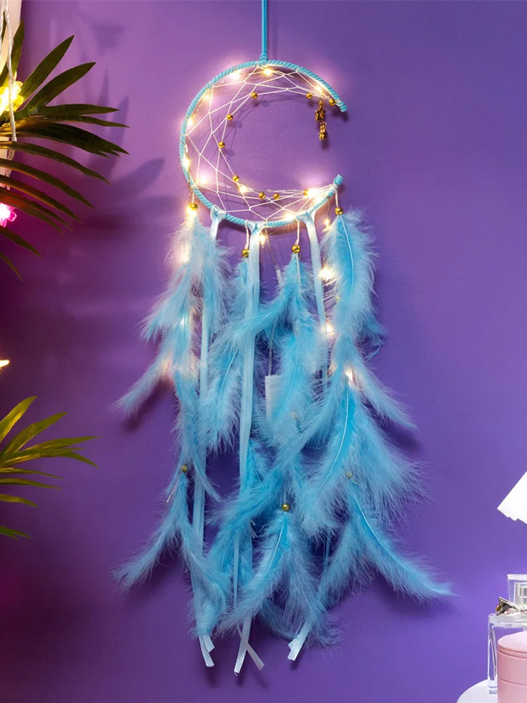 Turquoise dreamcatcher with feathers and string lights on a purple wall.