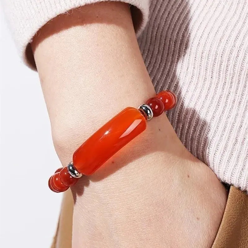 Close-up of a wrist wearing a red beaded bracelet with silver accents.