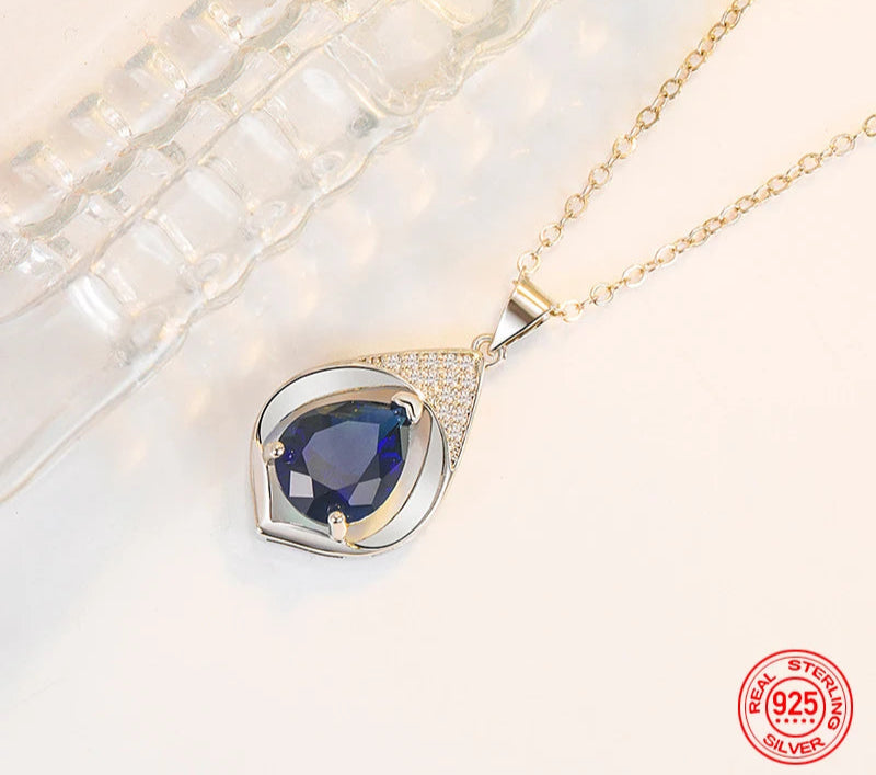 Gold necklace with a blue gemstone pendant on a white background, featuring the brand 'ZDADAN'.